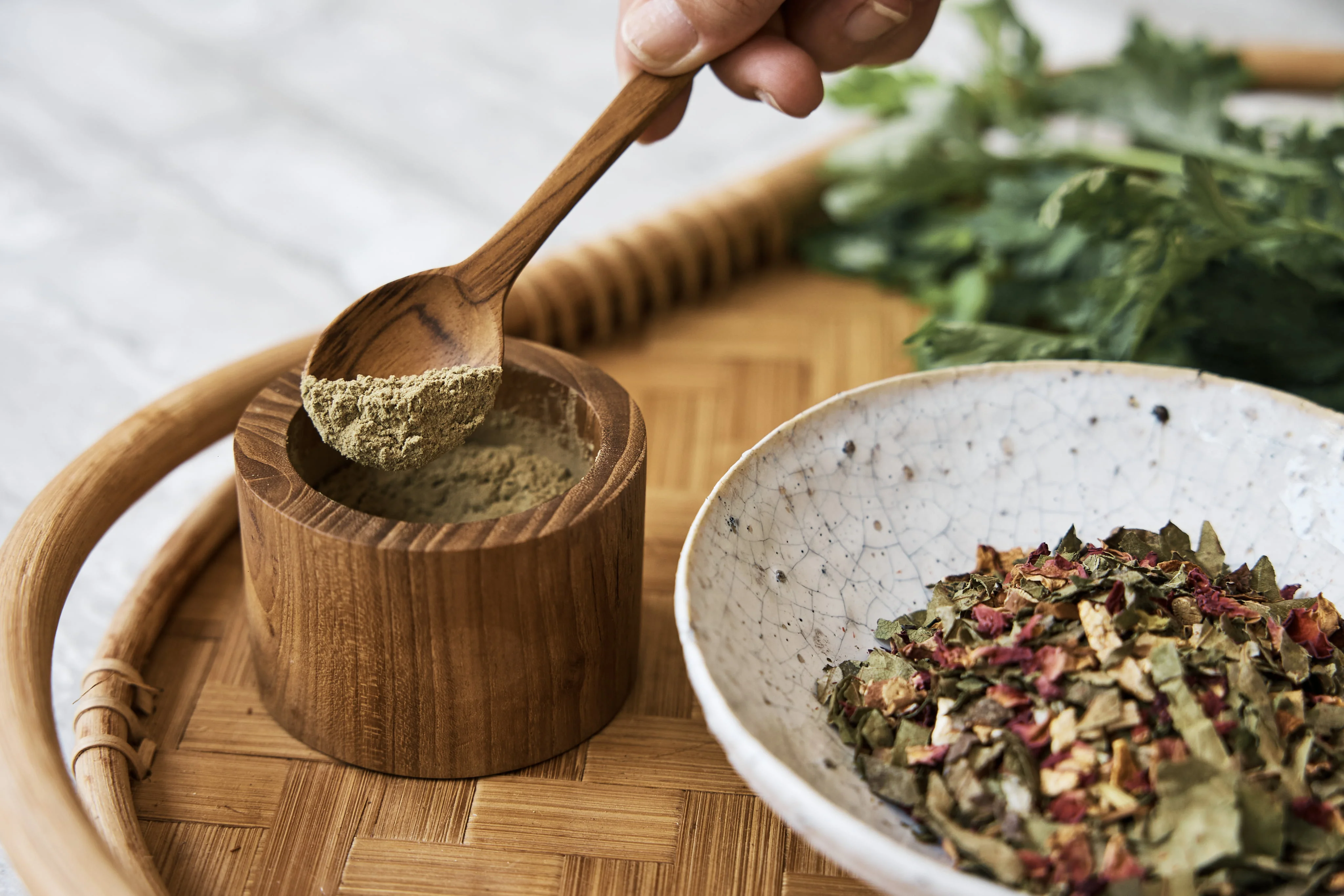 ハーブパウダーを木のボウルにすくい入れているところ
